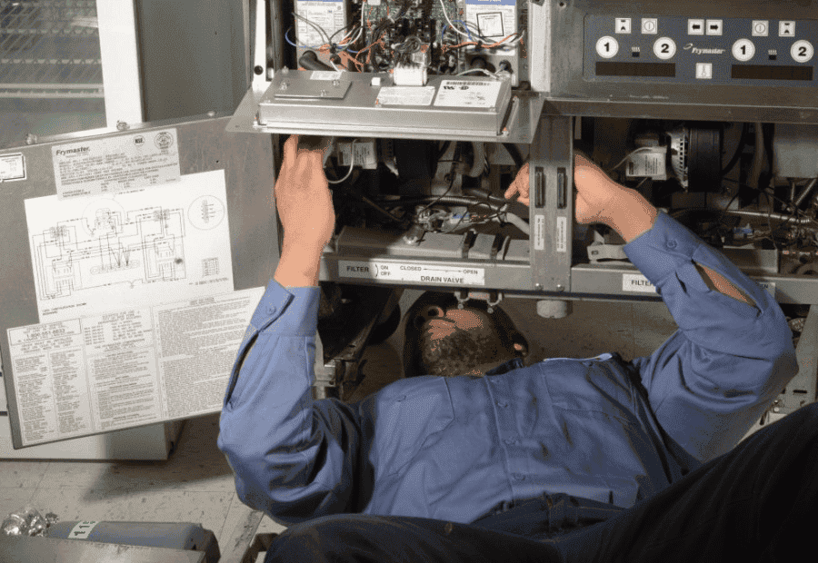 Man performing restaurant equipment repair in a food truck.